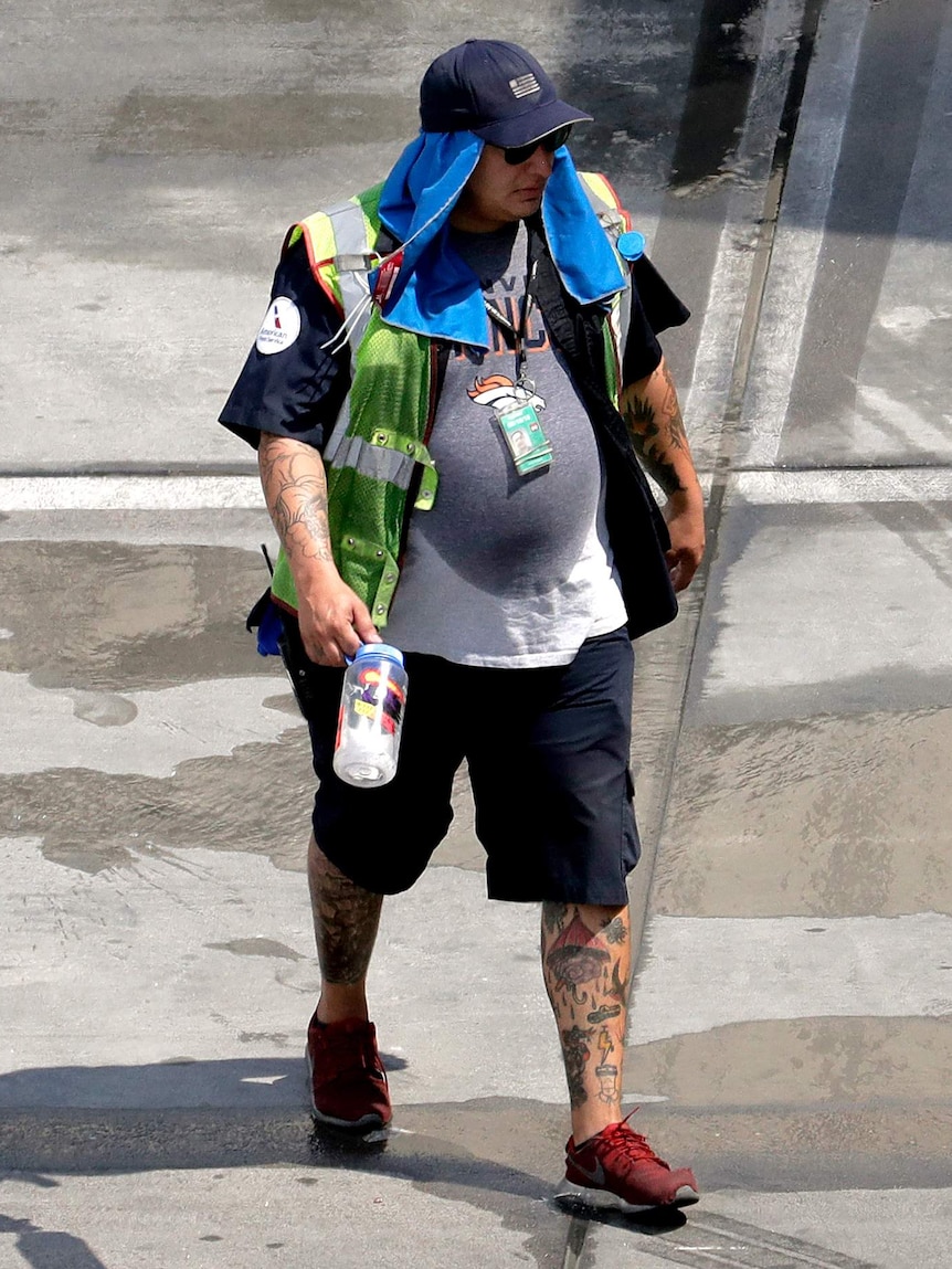 A sweaty ground crew member wears a cap and towel on his head