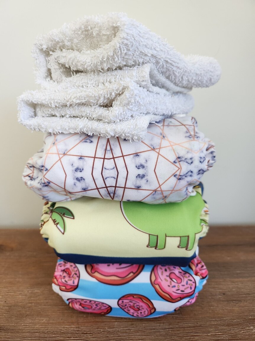 A pile of modern and traditional cloth nappies. The modern nappies have various patterns.