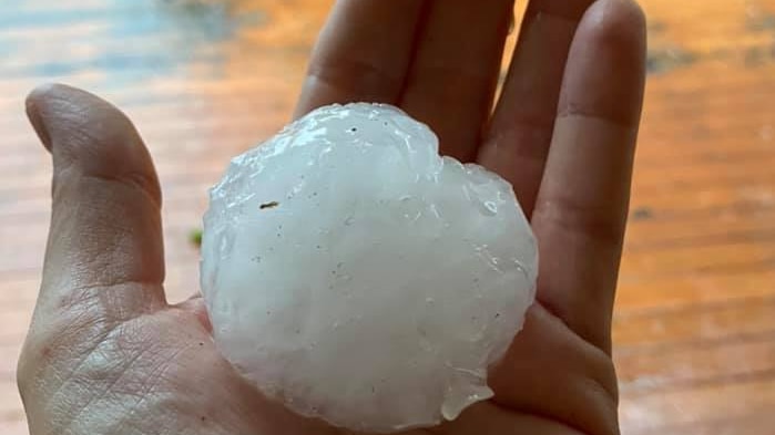 a hand holds a hailstone about the size of a tennis ball