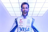 A man screams in excitement, wearing a white racing suit, during a promotional shoot