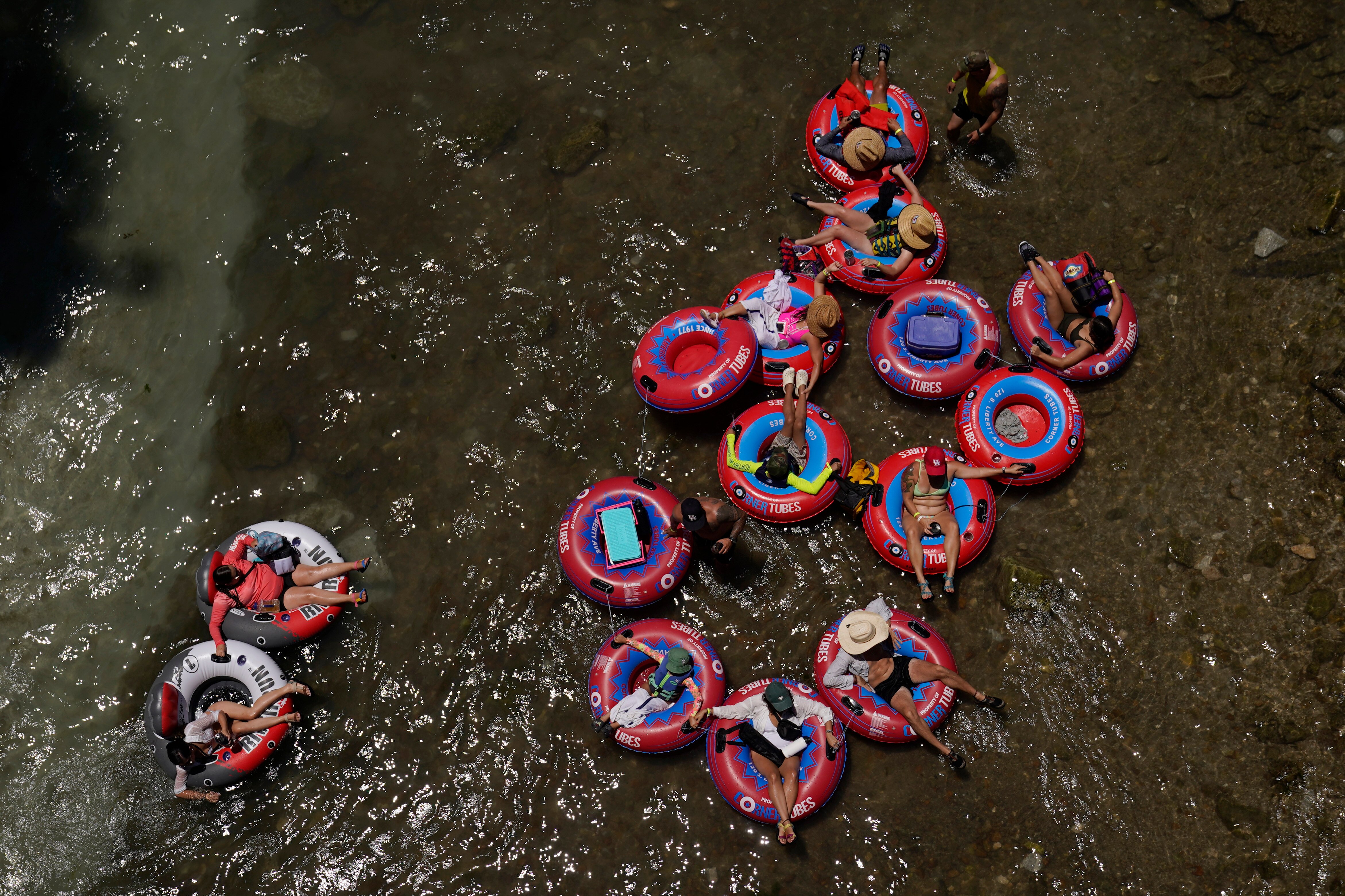 people sitting insite red floating tubes on top of the brown water 