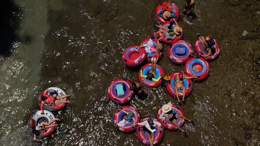 people sitting insite red floating tubes on top of the brown water 