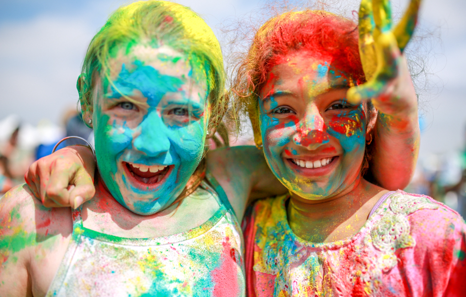Two girls covered in coloured powder with their arms around each other