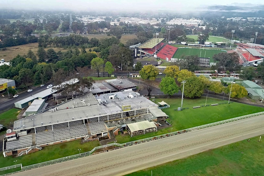 An aerial shot of a race track besides a stadium.