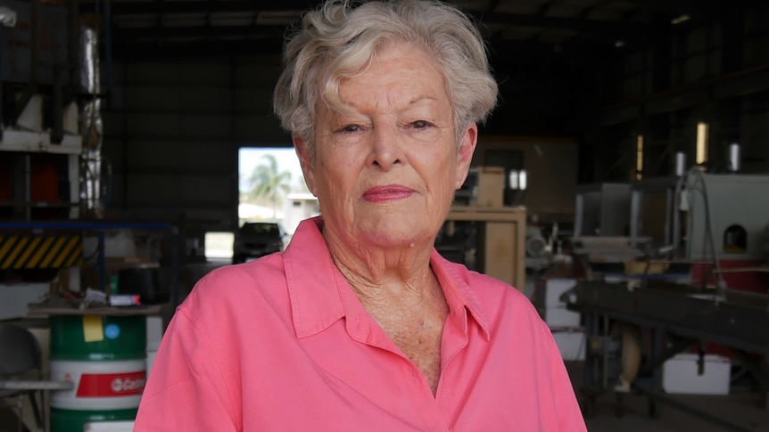 An older woman with short, grey hair wearing a bright top and looking perturbed.