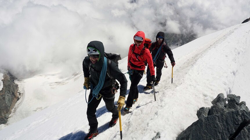 Steve Monks working as a climbing guide in the snow covered Allalinhorn in Switzerland, 4207m, with two other people behind him.