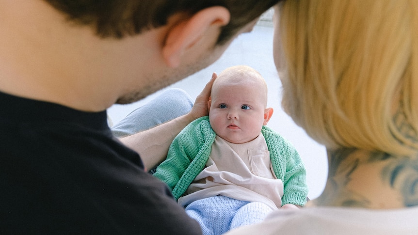 A couple holding and looking down at their new baby.