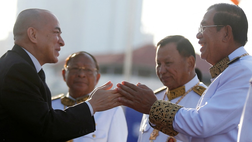Cambodia's King dressed in a black suit (left) greets Prime Minister Hun Sen dressed in white military dress.