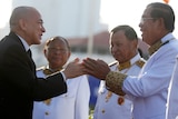 Cambodia's King dressed in a black suit (left) greets Prime Minister Hun Sen dressed in white military dress.