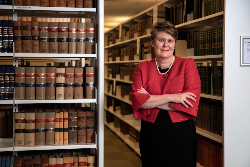 A woman stands amongst rows of books