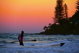 A man is silhouetted against the sunset at Burleigh Beach