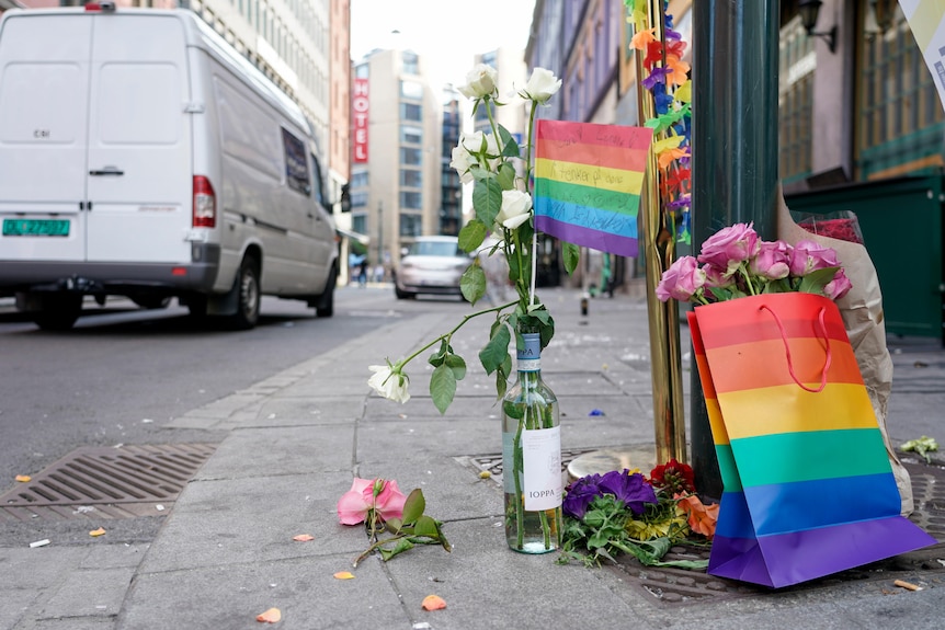 Flowers and rainbow flags left at street vigil.