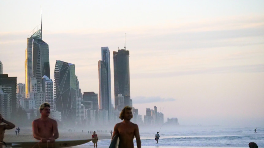 people on a beach in front tall buildings