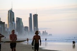 people on a beach in front tall buildings