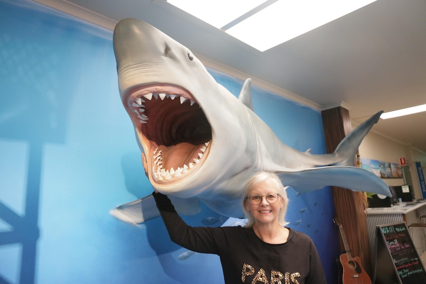 A women smiles next to a fake shark.
