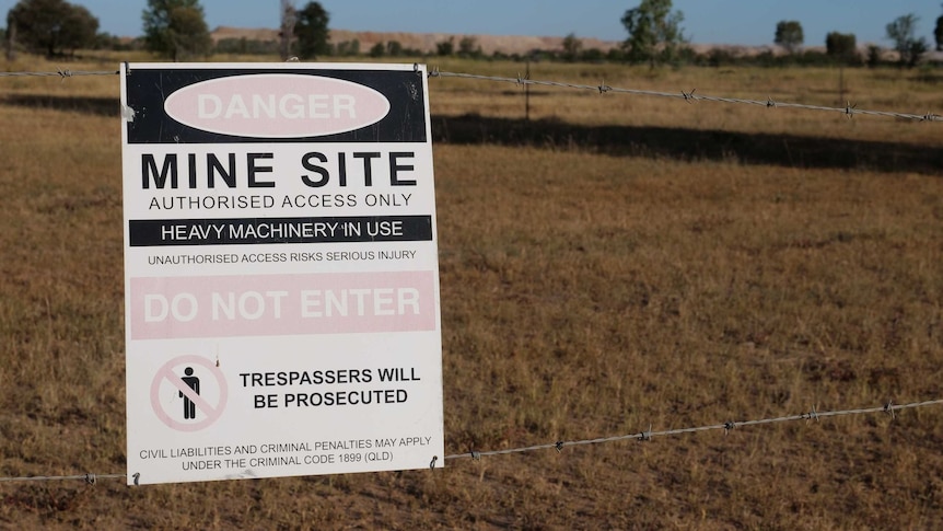 A sign on a barbed wire fence reads "mine site, authorised access only".