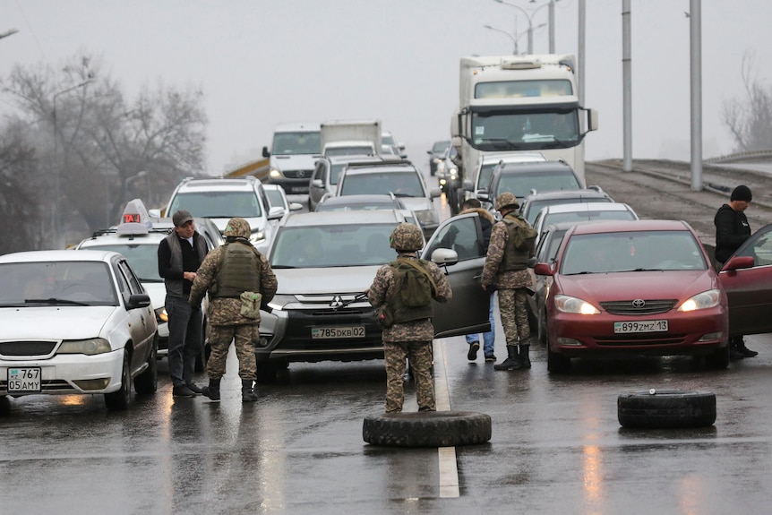 Kazakh law enforcement officers check vehicles on a road.