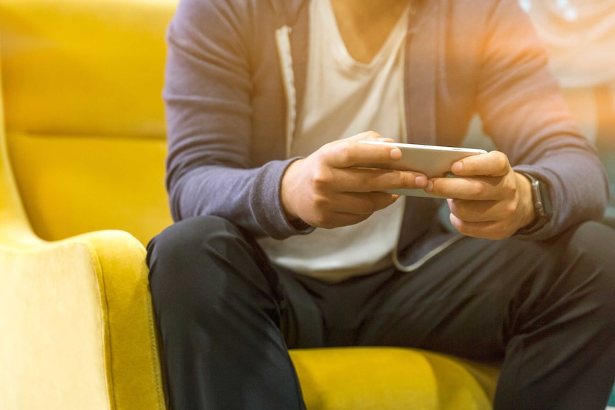 A man sitting on a couch looking at his phone.