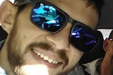 A man smiles with mirrored sunglasses on
