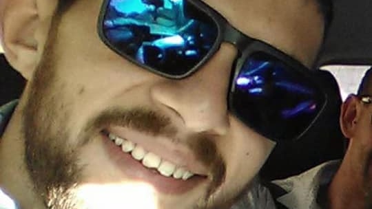 A man smiles with mirrored sunglasses on