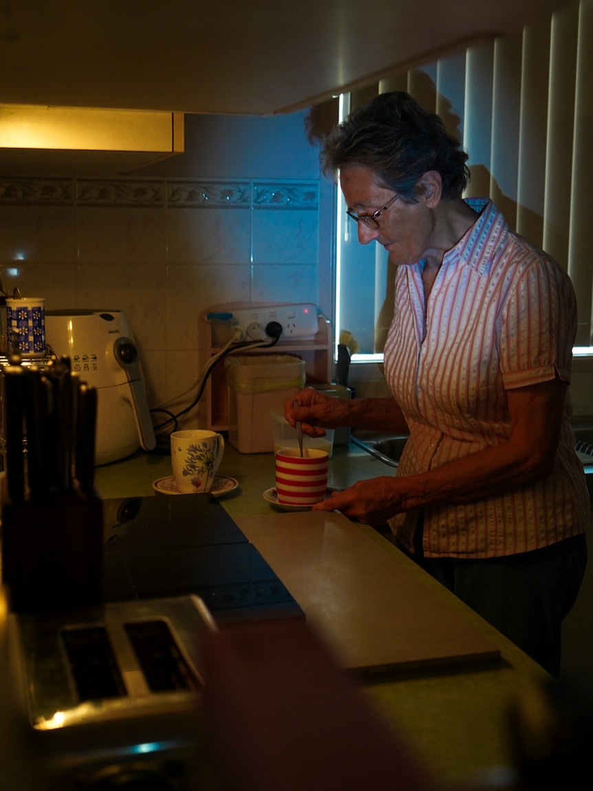 Gran making tea in dark kitchen 