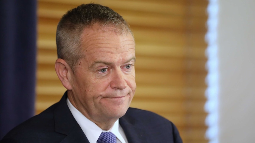 Shorten has a forced smile. He's wearing a blue suit and blue tie.