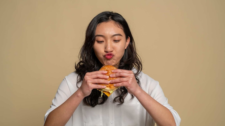 A young woman about to eat a burger.