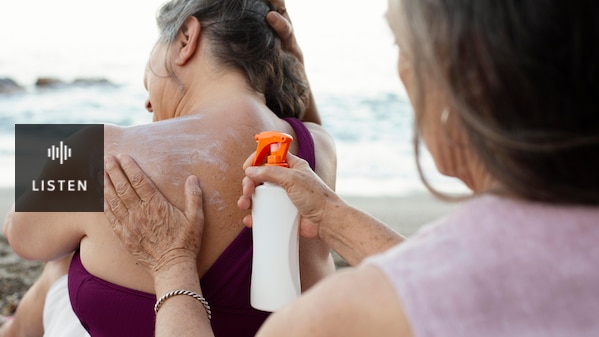 A lady applying sunscreen to another lady's back at the beach. Has Audio.