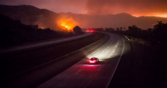 A car drives near a wildfire.