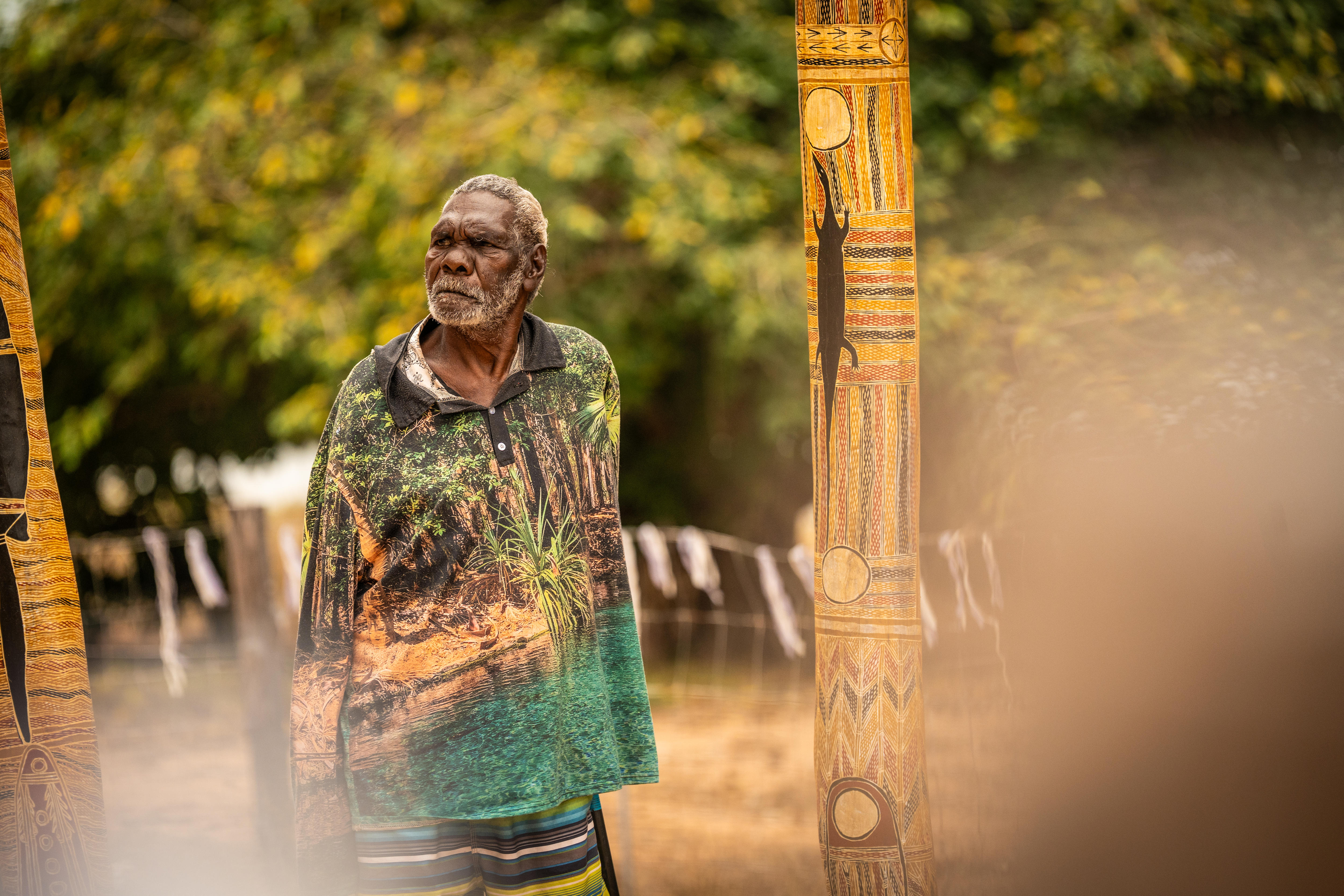 Un hombre se encuentra entre dos postes ceremoniales.