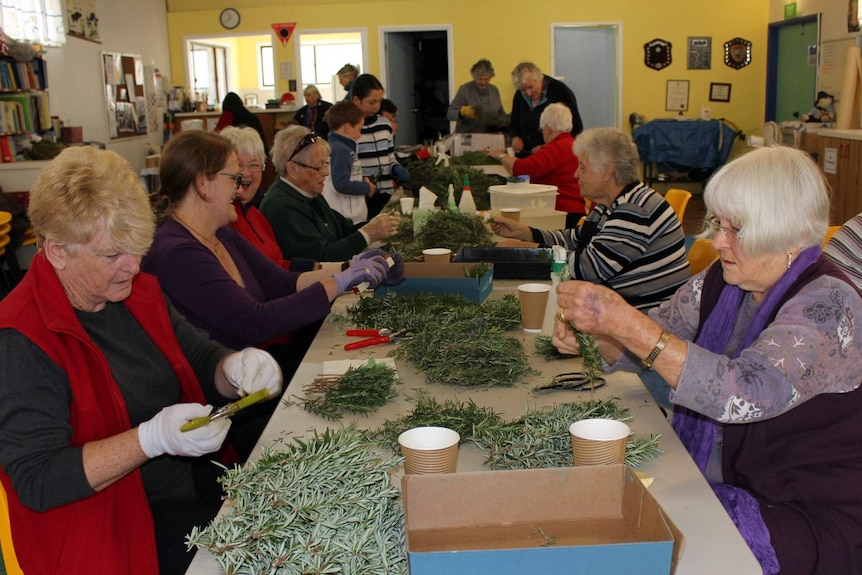 A group of women sprig rosemary at a table.