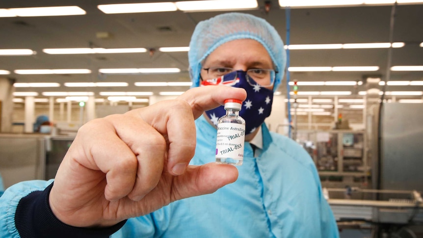 scott morrison holding a vial of a vaccine to the camera wearing pr
