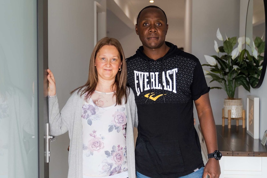 Emergency foster carers Angie and Gilbert Tsuro stand in the doorway of their home.