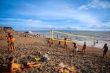 People laying around and playing volleyball on a tropical beach