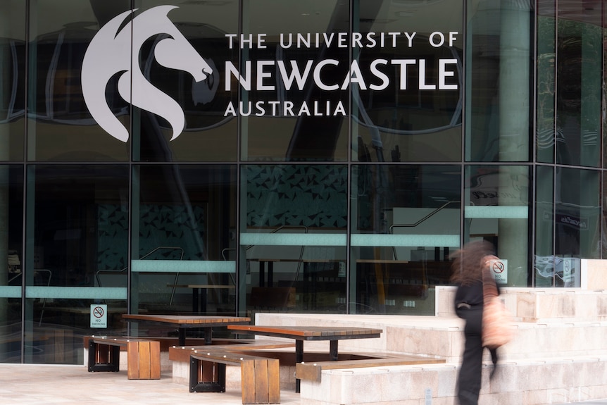 Exterior of a University of Newcastle building with an out-of-focus person walking past