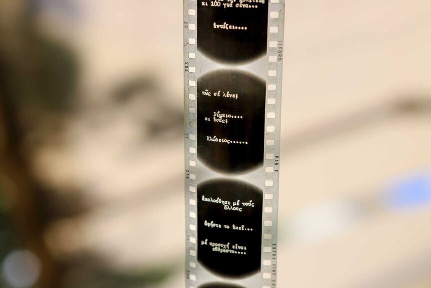 Close-up of a film negative with white Greek words across them.