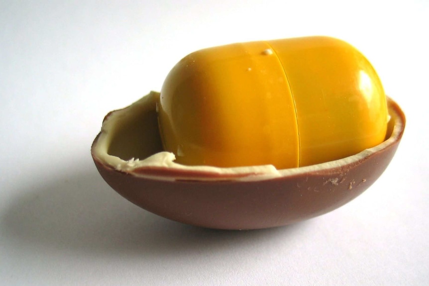 A Kinder Surprise chocolate egg cut in half, with a toy inside a plastic shell.
