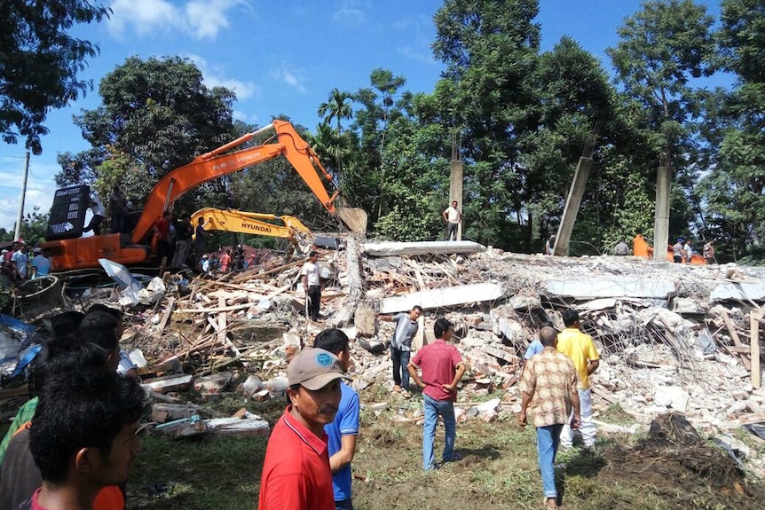 Rescuers use heavy machine to search for survivors under the rubble of a collapsed building.