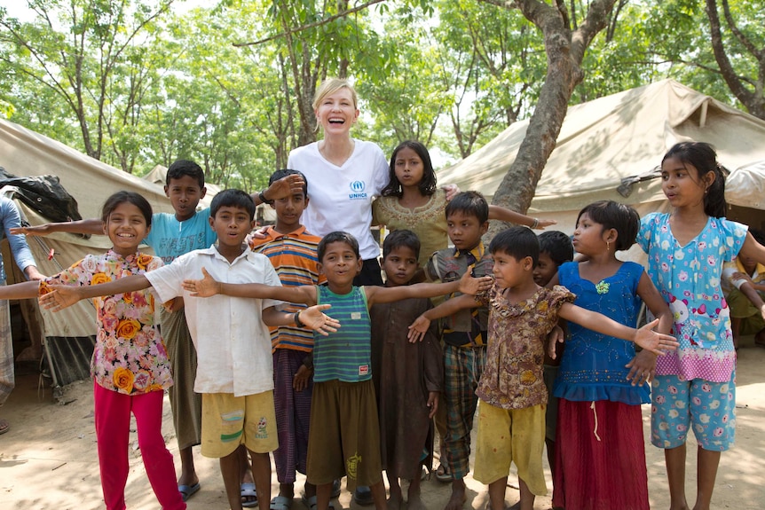 Cate Blanchett stands hugging Rohingya refugee children at a transit centre in Bangladesh.