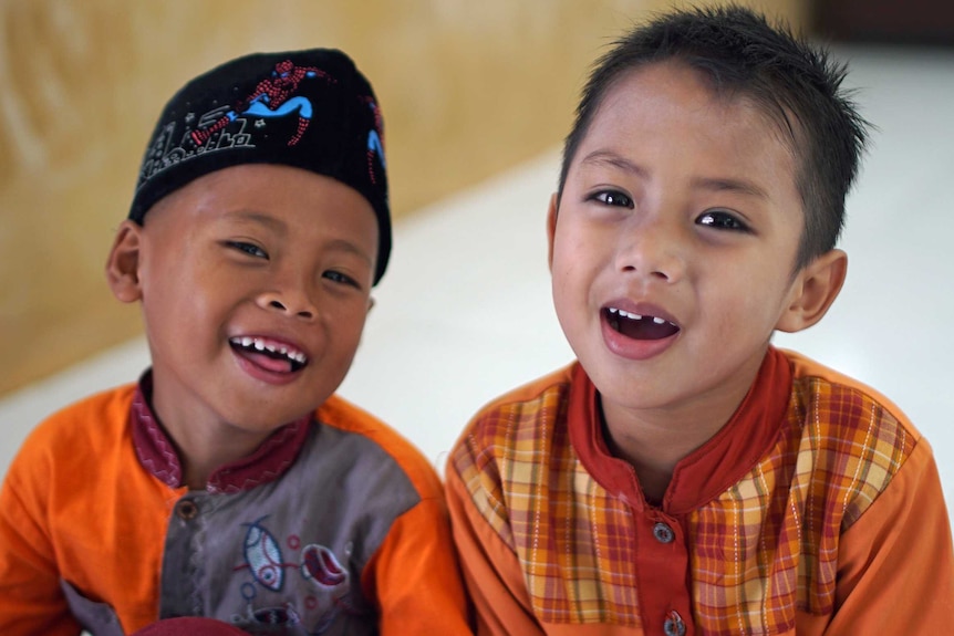 Two children at a class at the Peace Circle. They are smiling at the camera, one is wearing a Spiderman hat.