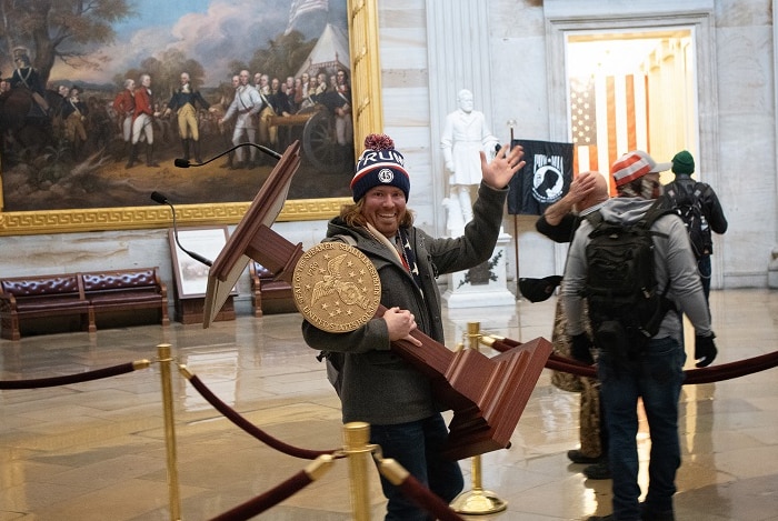 A rioter smiling as he carries off a lectern from the House of Representatives.