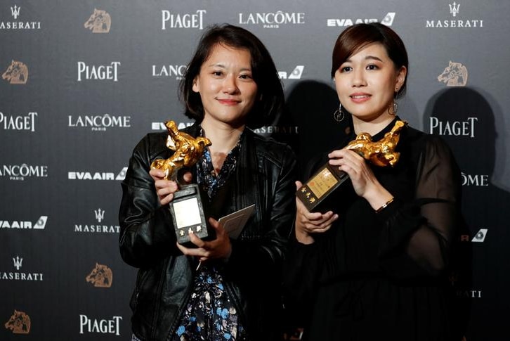 Two women hold trophies.