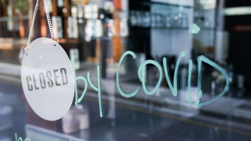 A business has written on its window, 'closed by covid'.