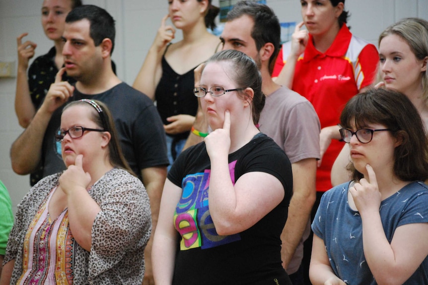 A group of people can be seen wearing casual clothes and doing sign language.