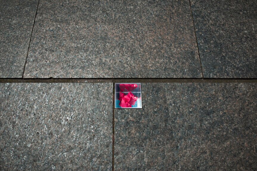 A small piece of floral paper can be seen in a glass box embedded in pavers.