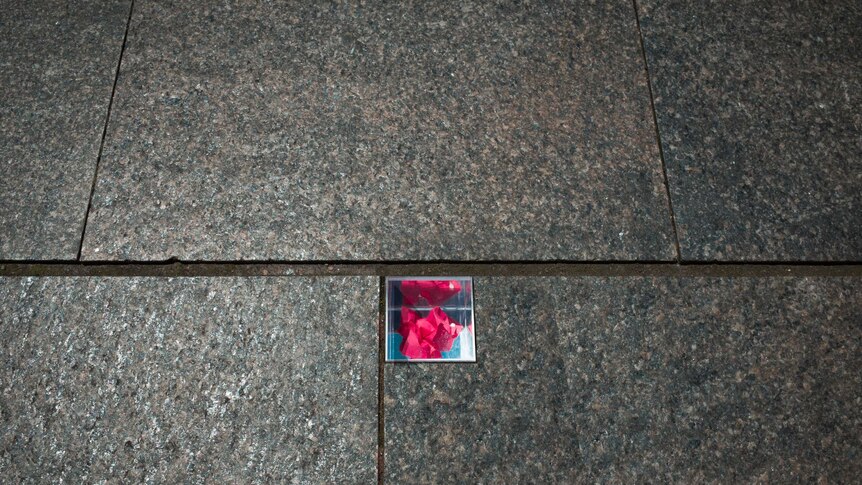 A small piece of floral paper can be seen in a glass box embedded in pavers.