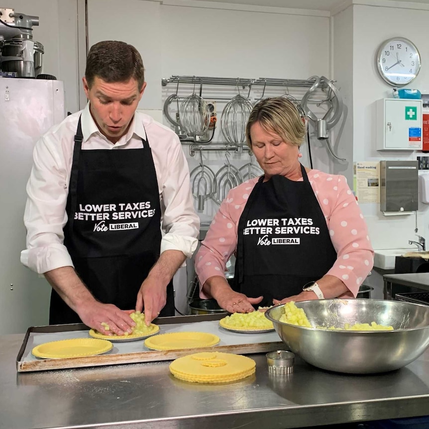Alistair Coe with Nicole Lawder in aprons with campaign slogans work dough for a pie crust.