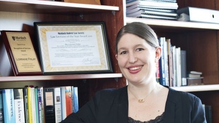 Woman in business suit standing in front of bookshelves