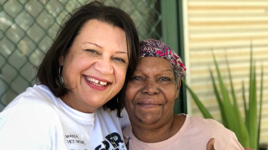 Two women in front of a home with green door