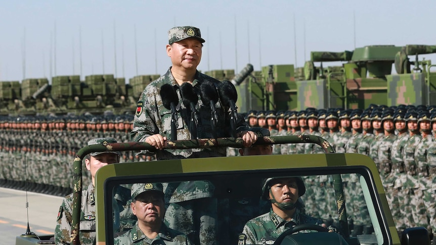 Chinese President Xi JinPing stands on a military jeep in full camouflage gear